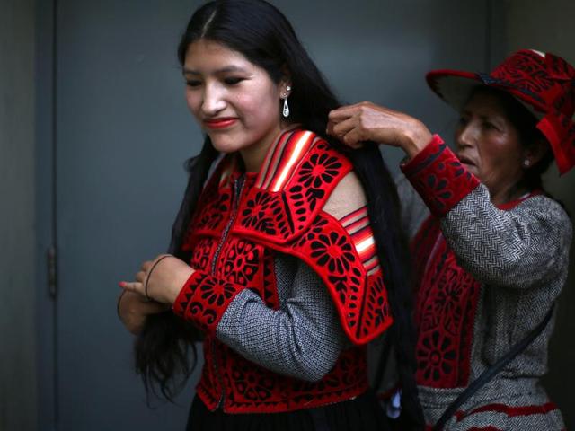 Andean indigenous dancer Waira Sacsi is helped with her hair by her mother Flor before the start of the ‘Takanakuy’ fighting ritual on the outskirts of Lima, Peru on Christmas day. Dancers open the event to traditional Andean music known as ‘Huaylia’. (AP) Andean indigenous dancer Waira Sacsi is helped with her hair by her mother Flor before the start of the ‘Takanakuy’ fighting ritual on the outskirts of Lima, Peru on Christmas day. Dancers open the event to traditional Andean music known as ‘Huaylia’. (AP)