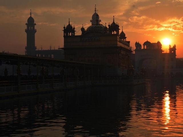 Devotees listen to the early Morning Prayer at the Golden Temple premises as the sun rises in the background. (Sameer Sehgal/HT Photo)