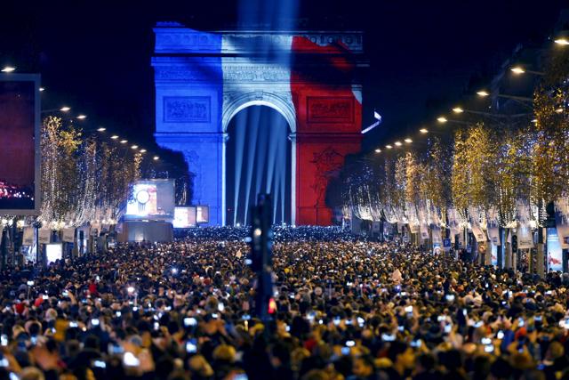 Revellers gather near the Arc de Triomphe which was lit with the blue, white and red colours of the French flag on the Champs Elysees Avenue in Paris. (REUTERS) Revellers gather near the Arc de Triomphe which was lit with the blue, white and red colours of the French flag on the Champs Elysees Avenue in Paris. (REUTERS)