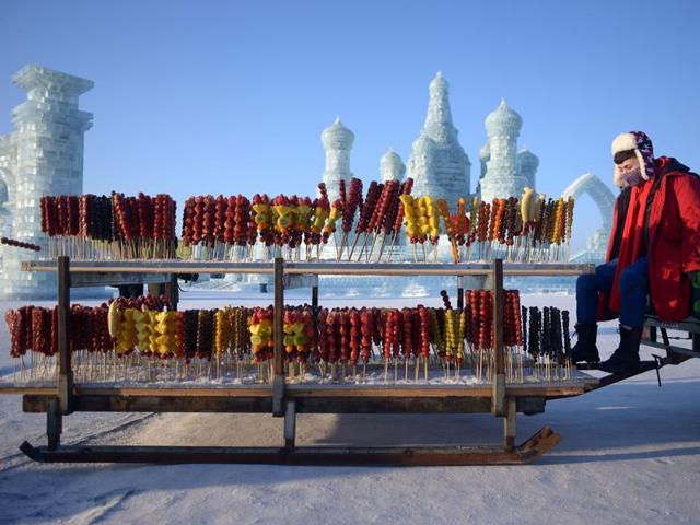 A vendor selling candied haws waits for customers at the China Ice and Snow World before the opening ceremony . (AFP) A vendor selling candied haws waits for customers at the China Ice and Snow World before the opening ceremony . (AFP)
