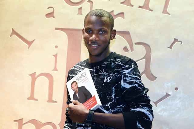 A picture taken on December 16, 2015 shows Lassana Bathily, the employee of the Hyper Cacher jewish supermarket in Paris who helped shoppers hide in a cold storage room from an Islamist gunman who attacked the store on January 9, 2015, posing with his book "Je ne suis pas un heros" (I Am Not A Hero).(AFP Photo)