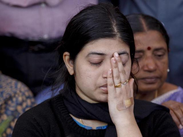 Wife Radhika, wipes her face as she sits next to the coffin of her husband and India's National Security Guard commando, Niranjan Kumar, who was among those killed in the attack on the Pathankot air force base after the body was brought to Bangalore. (AP)