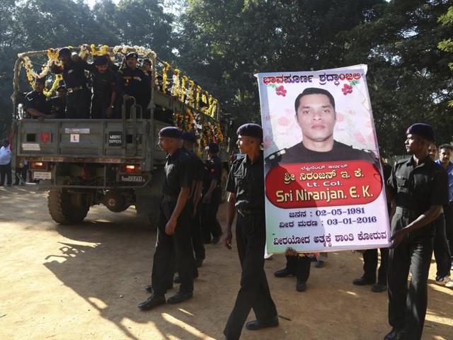 Indian army soldiers carry a portrait of National Security Guard commando, Niranjan Kumar, who was among those killed in the attack on the Pathankot air force base after his body was brought to Bangalore. (AP)