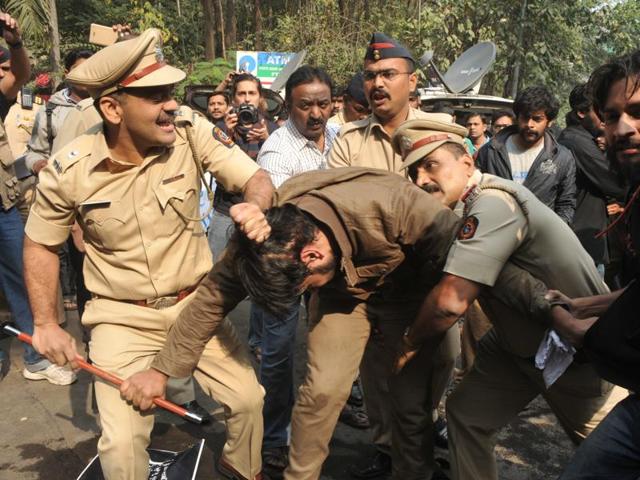 A cop pulls a demonstrator by his hair after students refused to clear the way for Chauhan. (HT photo)