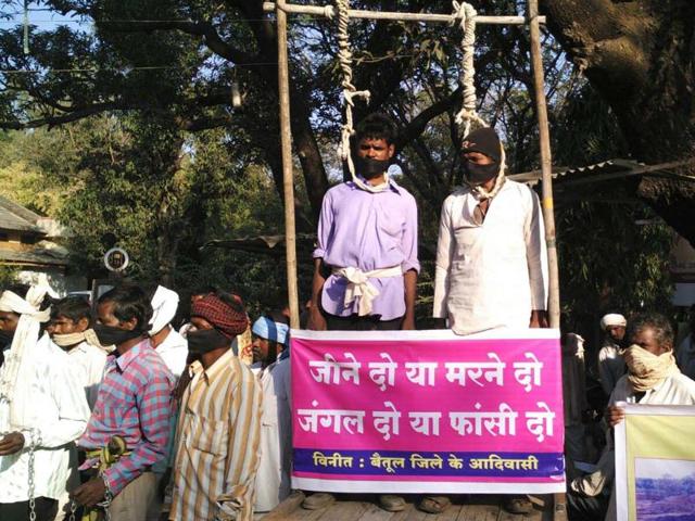 Agitating members of the Korku tribe protest at a market in Betul. The placards read ‘either give us forest land back or hang us’.(HT photo)