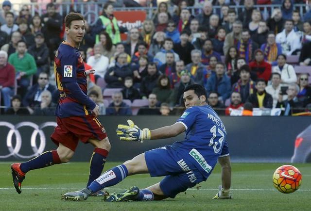 Barcelona's Lionel Messi scores a goal against Granada's goalkeeper Andres Fernandez. (Reuters Photo)