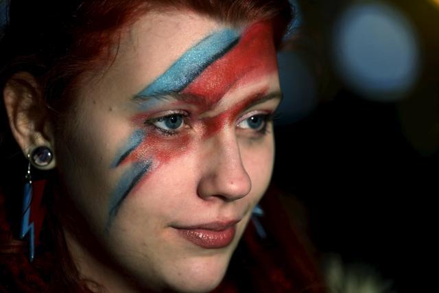 A fan of David Bowie joins other revellers to celebrate the life of the musician and singer, after the announcement of his death at Brixton in London, January 11, 2016. (REUTERS) A fan of David Bowie joins other revellers to celebrate the life of the musician and singer, after the announcement of his death at Brixton in London, January 11, 2016. (REUTERS)