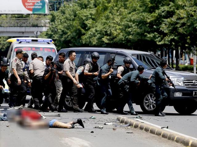 Dead bodies are seen as Indonesian police hold rifles while walking behind a car for protection. (Reuters Photo) 