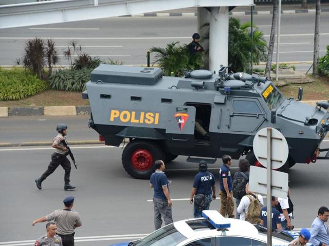 Indonesian police commandos backed by an armored vehicle secure the area outside a damaged Starbucks coffee shop after a series of explosions hit central Jakarta. (AFP Photo) 
