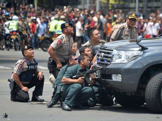 Indonesian police take position behind a vehicle as they pursue suspects after a series of blasts hit the Indonesia capital Jakarta. (AFP Photo) 