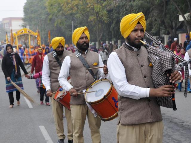 Sewadars clean the road while several artists play musical instruments as the religious procession follows in SAS Nagar on Thursday. (Gurminder Singh/HT Photo)