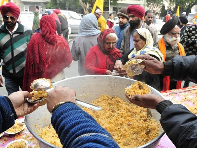 Sewadars distribute rice as prashad (sacred food) to the devotees gathered during the procession in Chandigarh on Thursday. (Keshav Singh/HT Photo)