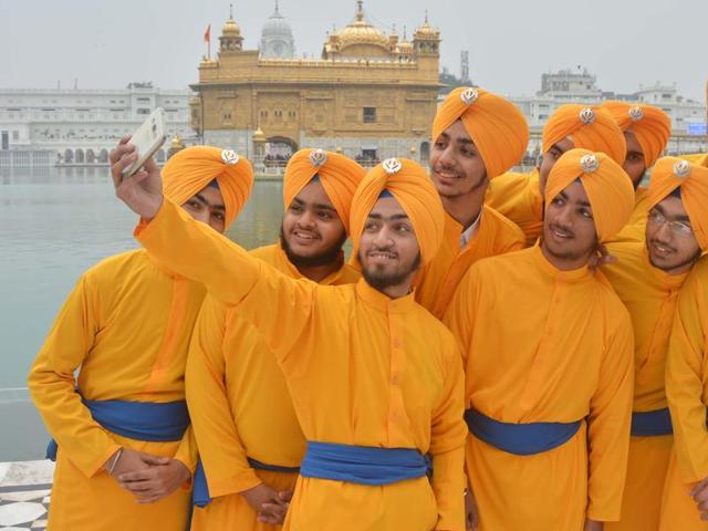 Young Sikh devotees taking a selfie on the eve of birth anniversary of the tenth Sikh guru at Golden Temple in Amritsar. (Sameer Sehgal/HT )