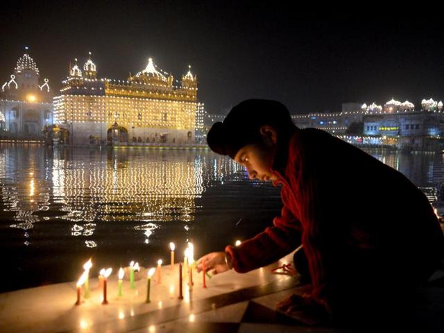 A child lighting candles at the Golden Temple on the occasion of birth anniversary of Guru Gobind Singh in Amritsar on Saturday. (Sameer Sehgal/HT Photo)
