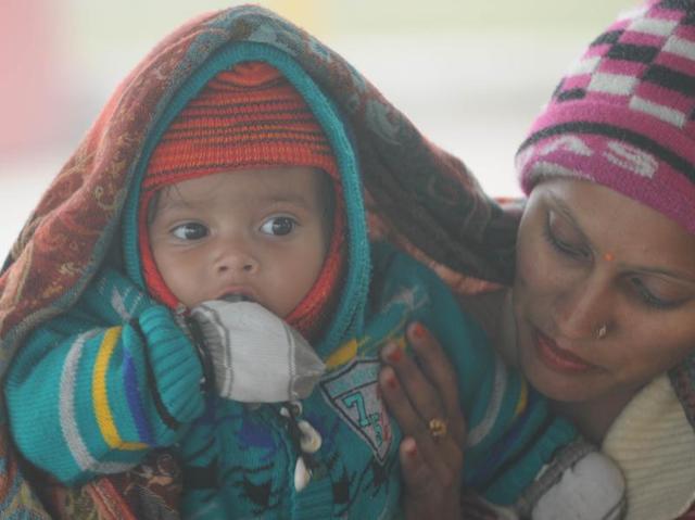 A woman covers her child with a shawl to save him from the frosting winter in Patiala on Monday. (Bharat Bhushan/HT Photo )