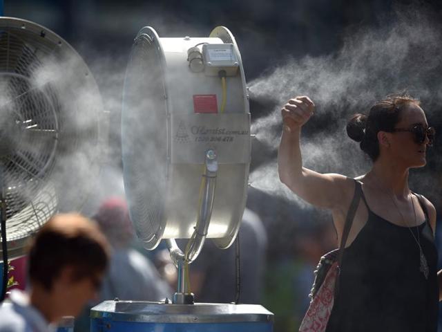 A woman cools herself down as she stands next to a mist fan on day one of the 2016 Australian Open. (AFP Photo)