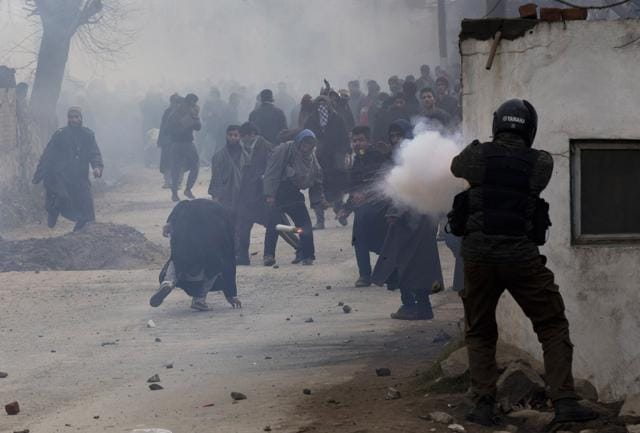 A police officer fires a teargas shell as a protester, (C) ducks to avoid it during the funeral procession for a separatist leader on the outskirts of Srinagar.(AP) A police officer fires a teargas shell as a protester, (C) ducks to avoid it during the funeral procession for a separatist leader on the outskirts of Srinagar.(AP)