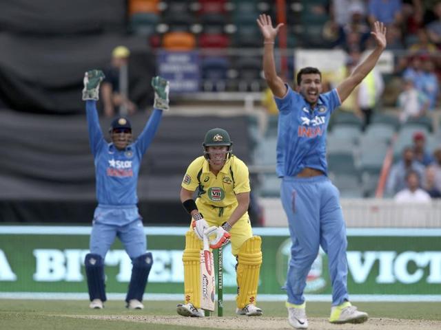 Australian batsman David Warner, center, watches as Rishi Dhawan, right, and MS Dhoni appeal for an LBW decision. (AP Photo) 