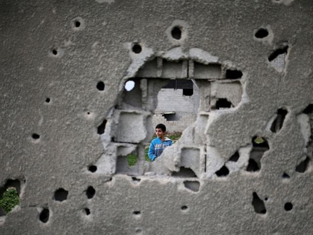 A Palestinian boy is seen through a bullet-riddled wall from a building which was destroyed during the 50-day war between Israel and Hamas in 2014, Gaza City. (AFP File Photo) A Palestinian boy is seen through a bullet-riddled wall from a building which was destroyed during the 50-day war between Israel and Hamas in 2014, Gaza City. (AFP File Photo)