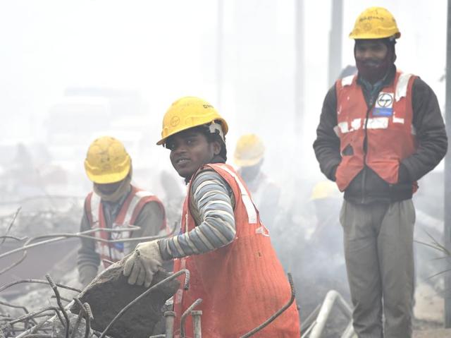 ‘...but the show must goes on’: No matter how cold, foggy or unfavourable working conditions in the cold capital are, workers secured in gloves and helmets, toil at a construction site.  (Ajay Aggarwal/ HT PHoto) 