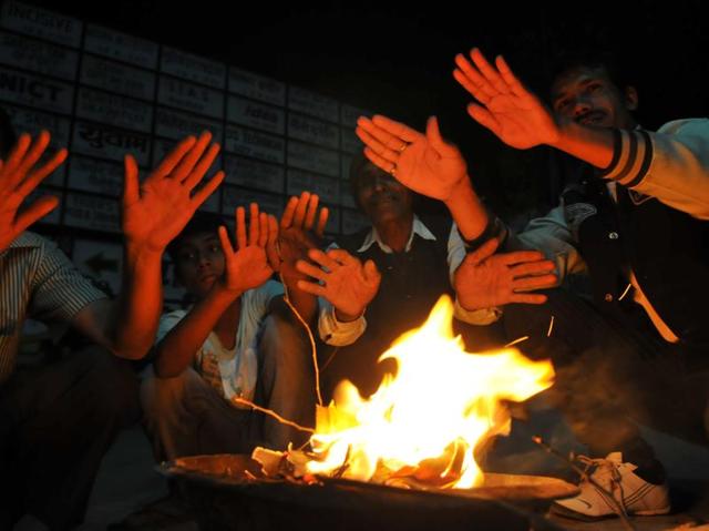 As temperature in the city drops, people take some guard against cold as they gather around a bonfire. (Shankar Mourya/ HT Photo ) 