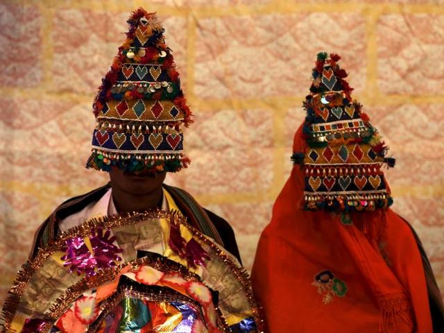 A bride and groom wearing traditional handmade garlands wait for their wedding to start in Karachi. (REUTERS)