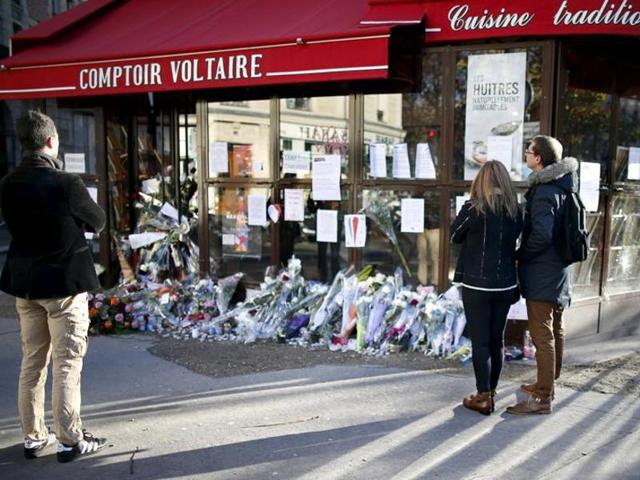 People stop to look at flowers, candles and messages in tribute to victims in front of the Comptoir Voltaire cafe, one of the sites of the deadly attacks in Paris, France, November 21, 2015.(REUTERS)