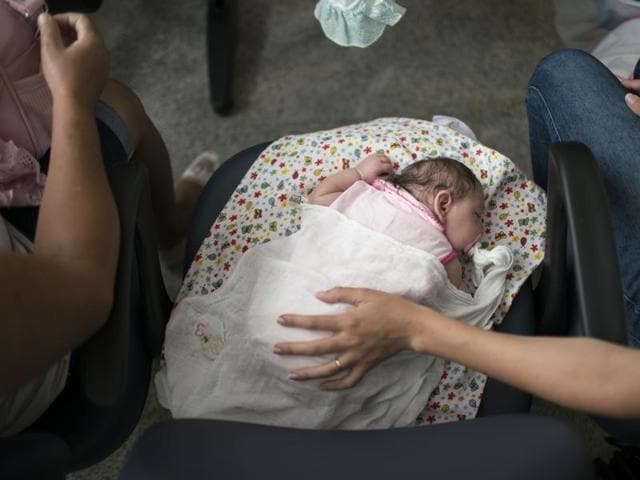 Dejailson Arruda holds his daughter Luiza at their house in Santa Cruz do Capibaribe, Pernambuco state, Brazil. ) (AP) Dejailson Arruda holds his daughter Luiza at their house in Santa Cruz do Capibaribe, Pernambuco state, Brazil. ) (AP)