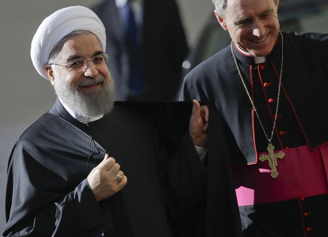 Prefect of the Papal Household Monsignor Georg Gaenswein welcomes Iranian President Hassan Rouhani (L) upon his arrival at the San Damaso courtyard for his private audience with Pope Francis, at the Vatican. (AP Photo)
