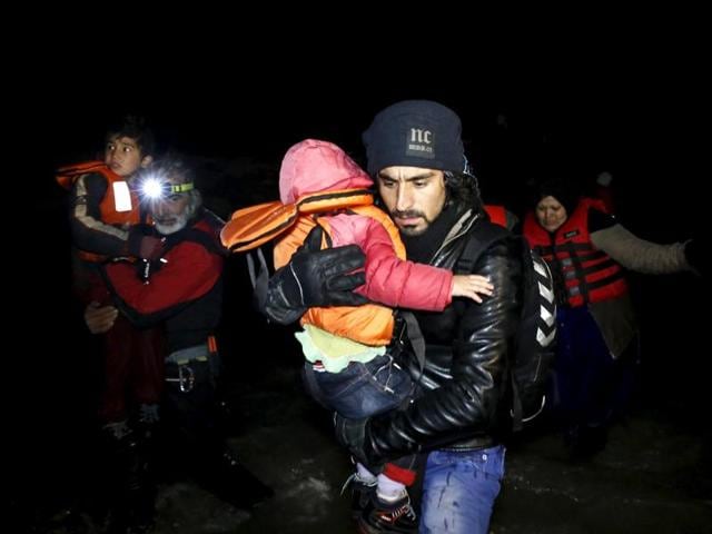 An Afghan migrant carries a child as he arrives with other Afghan migrants on a raft on the Greek island of Chios. (REUTERS) An Afghan migrant carries a child as he arrives with other Afghan migrants on a raft on the Greek island of Chios. (REUTERS)
