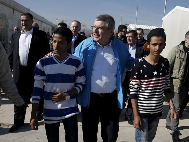 International Olympic Committee chairman Thomas Bach plays football with youths during a visit to the Elaionas camp for migrants and refugees in Athens on January 28, 2016. IOC has said that a refugee will be among the torch bearers at the Rio Olympics.(AFP)