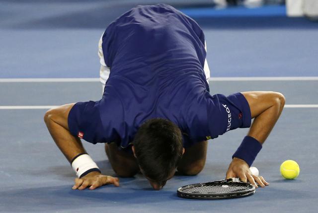 Just as Rafael Nadal bites all his trophies, kissing the court is becoming a bit of a Novak Djokovic tradition. At Wimbledon, he takes a bite of the grass, literally. (Reuters Photo)