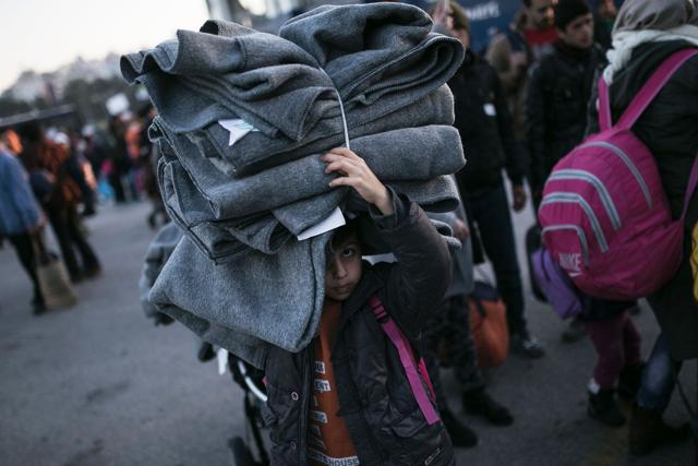 A migrant boy holds blankets as he disembarked from the passenger ferry Blue Star arriving from the Greek island of Lesbos at the port of Piraeus on January 31, 2016 in Athens. (AFP)