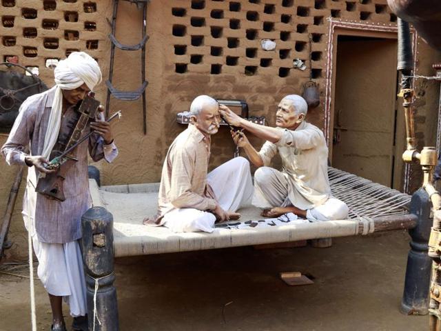 Surajkund Mela: Statues and an artiste at the Apna Ghar section of the international arts and crafts fair near Faridabad on Tuesday. (HT photo)