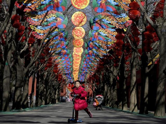 A girl rides on a child’s scooter under decorations for a temple fair ahead of Chinese Lunar New Year (February 8) at Ditan Park in Beijing on February 2, 2016. (AP) 