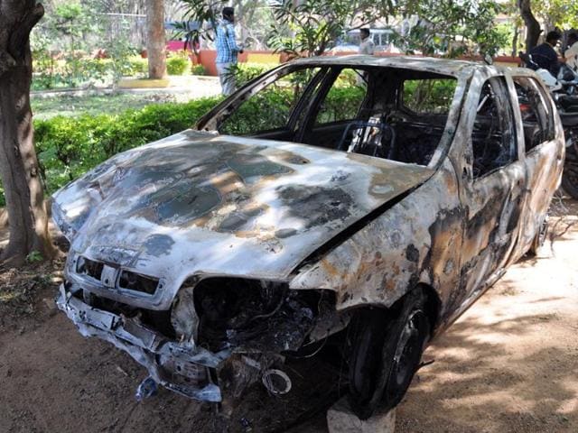 Indian pedestrians walk past the spot where a vehicle was set ablaze by a mob in Bangalore. (AFP) Indian pedestrians walk past the spot where a vehicle was set ablaze by a mob in Bangalore. (AFP)