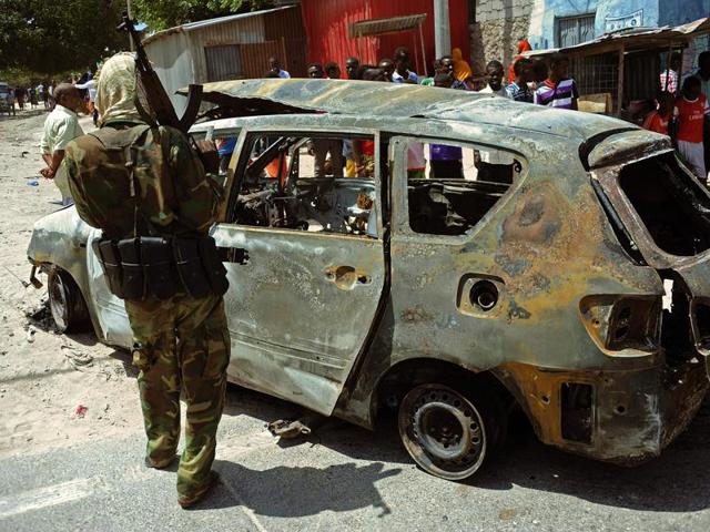 A soldier stands near a burnt car at the scene of a car bomb on February, 5, 2016 in Mogadishu.(AFP)