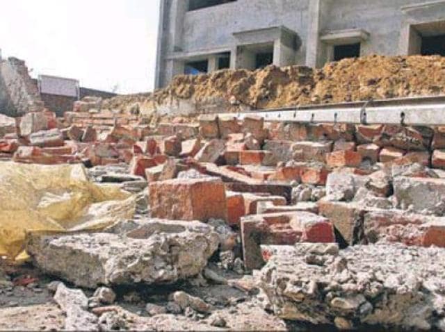A ragpicker died as a 35-foot-long wall of the municipal corporation dump near the books market collapsed on Friday morning. Three stray dogs that were sleeping along the wall were also buried under the debris and died.(HT Photo)