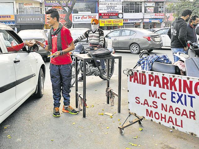 A parking fee collecter on duty at a paid parking lot in SAS Nagar.(Gurminder Singh/HT Photo)