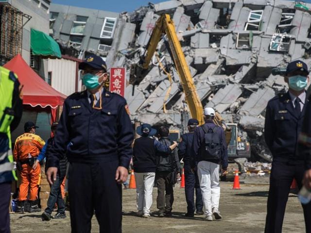 A general view shows excavator vehicles and rescue workers in front of a building (background) which collapsed in the 6.4 magnitude earthquake in the southern Taiwanese city of Tainan on February 9, 2016.(AFP)