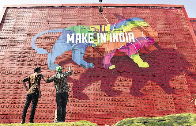Workers carry a cutout of the Make In India logo at BKC. (Pratham Gokhale/HT photo)