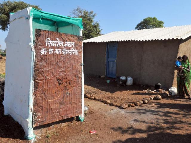 A woman in Indore’s Nayagaon village stands in front of a toilet built on Simrol model of low-budget toilets.(Shankar Mourya/ HT file)