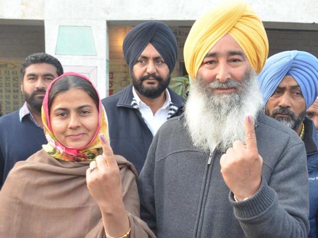 SAD candidate Ravinder Singh Brahmpura and his wife Ravinder kaur showing their index finger after casting their vote at their native village in Khadoor Sahib. (Sameer Sehgal/ HT)