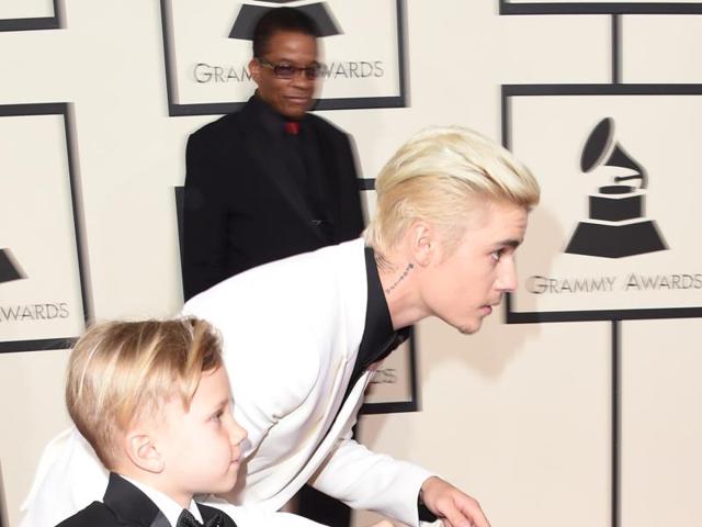 Singer-songwriter Justin Bieber runs with his brother Jaxon on the red carpet for the 58th Annual Grammy music Awards in Los Angeles February 15.  (AFP) 