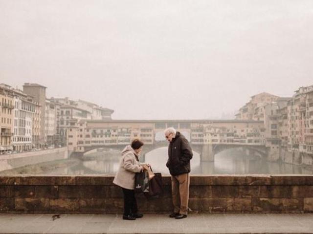 An elderly couple on a pretty street. Perhaps she is asking him to hold some bags.  (Instagram/cardenosahector) 