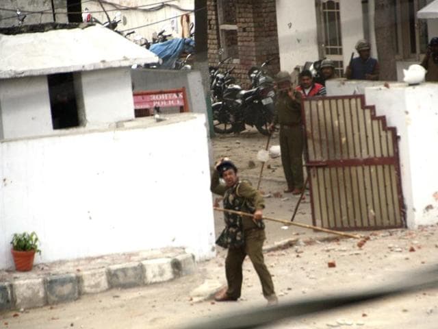A cop is seen throwing stones at protesting Jat students in front of IGP office, Rohtak on Friday.The community has been demanding for reservation in government jobs. (Manoj Dhaka/HT )