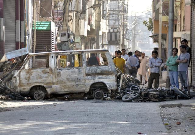 People stand behind damaged motorcycles and a van that were set alight by protesters during a demonstration by Jat protesters in Rohtak, in Haryana. (REUTERS) People stand behind damaged motorcycles and a van that were set alight by protesters during a demonstration by Jat protesters in Rohtak, in Haryana. (REUTERS)