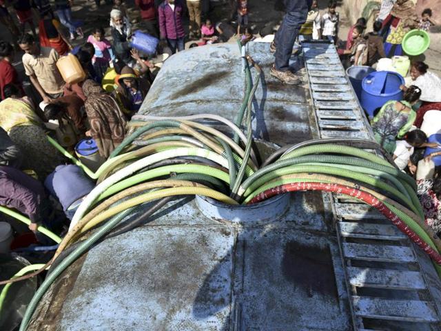 Residents with empty containers gather around a municipal tanker to fetch water in New Delhi.(Vipin Kumar/HT Photo)