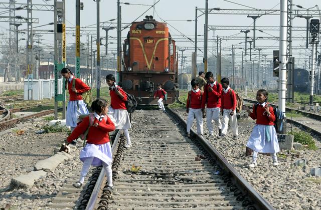Schoolchildren cross rail tracks as they journey home after school, at Jalandhar city railway station. (AFP)