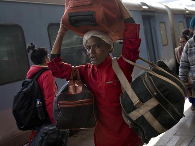A porter carries bags of a passenger at a train station in New Delhi. Porters will not be called ‘coolies’ but ‘sahayaks’ now, railway minster Suresh Prabhu said on Thursday.  (AP Photo) 